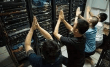 a group of people are giving each other a high five in a server room .