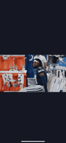 a man in a football uniform is standing in front of a display of cowboys shirts .