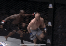 two men are fighting in a boxing ring and one of them is wearing shorts with the word ufc on them