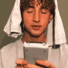 a young man with a towel wrapped around his head is taking a selfie with his phone .