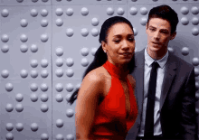 a man and a woman are standing next to each other in front of a wall with dots on it .