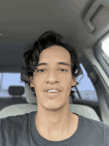 a man with curly hair is sitting in the back seat of a car