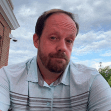 a man with a beard wears a light blue shirt