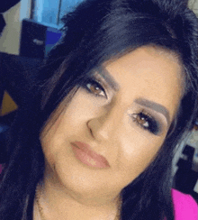 a close up of a woman 's face with a pink shirt and a necklace .