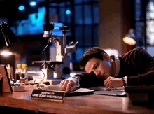 a man laying on a desk with a barry allen crime scene investigator sign on it