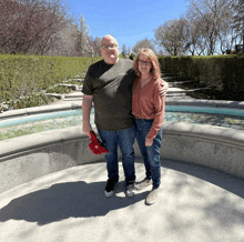 a man and a woman standing in front of a fountain with the man wearing a shirt that says ' columbia '