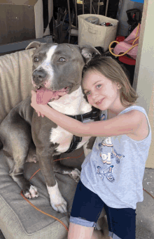 a little girl is hugging a dog that is wearing a shirt that says butterfly on it