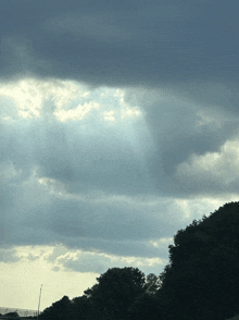 the sun is shining through the clouds over a forest