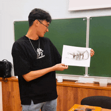 a man wearing a black energy shirt holds up a drawing of a scorpion