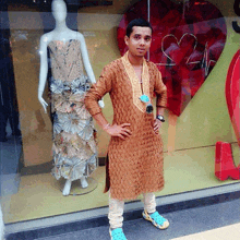 a man standing in front of a mannequin wearing a dress made out of newspaper