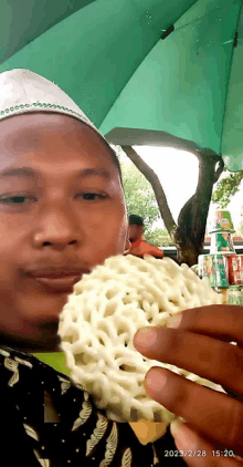 a man wearing a white hat is eating a cracker with the date 2023/2/28 on the bottom right