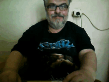 a man with glasses and a beard wears a black shirt that says ' heavy ' on it