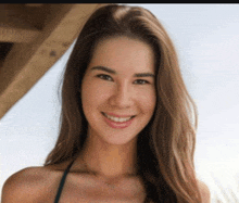 a woman in a bikini is smiling and wearing a necklace