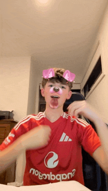 a boy wearing a red adidas shirt with a dog face mask on his face