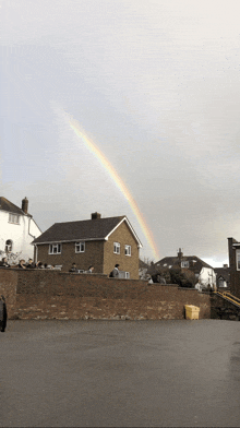 a rainbow is visible over a brick house