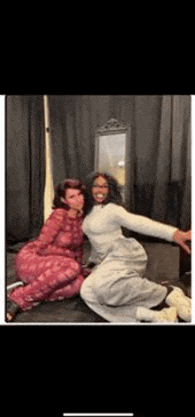 two women are posing for a picture together in a bedroom .