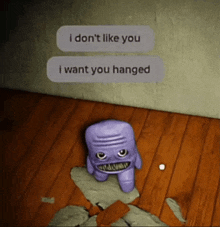 a purple stuffed animal is sitting on a wooden floor next to a wall that says i don t like you