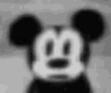 a black and white photo of mickey mouse 's face with a blurred background .