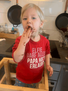 a little boy wearing a red shirt that says elfie darf alles