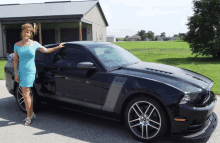 a woman in a blue dress stands next to a mustang boss 302