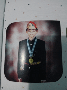 a young boy wearing glasses and a medal around his neck has a red hat on