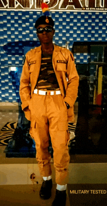 a man in a military uniform is standing in front of a wall that says military tested