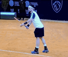 a man is holding a tennis racquet on a tennis court with a banner behind him that says federacao portuguesa us