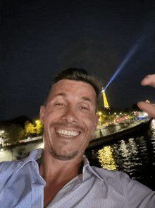 a man smiles in front of the eiffel tower