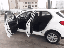 a white car with the doors open is parked on a concrete surface