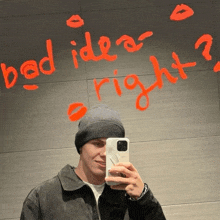 a man is taking a picture of himself in front of a wall that says " bad idea right "