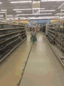 a child sits on a green hopper in an aisle of a store with a sign that says 10 %