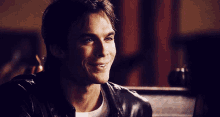 a man wearing a black leather jacket is smiling for the camera