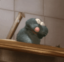 a stuffed animal with big eyes and a pink nose is sitting on a shelf