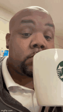 a man drinking from a starbucks cup with a green star on it