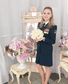 a woman in military uniform holds a bouquet of flowers