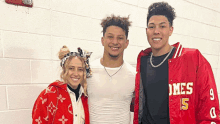 two men and a woman are posing for a picture and one of the men is wearing a louis vuitton jacket