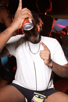 a man in a white shirt is holding a red can of soda