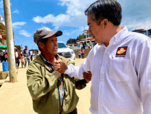 a man wearing a shirt that says " frente nacional " talks to a man