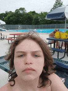 a boy with long hair is taking a selfie in front of a pool