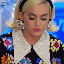 a close up of a woman wearing a headband and pearls .