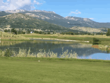 a golf course with mountains in the background and a lake in the middle