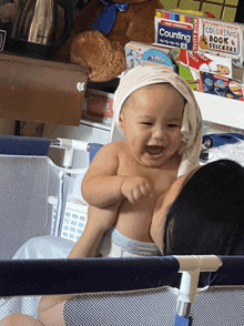 a baby with a towel wrapped around his head is being held by a woman in front of a stack of counting books