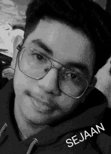 a black and white photo of a young man wearing glasses and the name sejaan written on the bottom