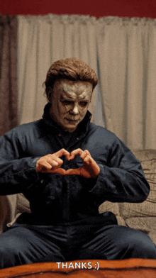 a man in a mask is making a heart with his hands