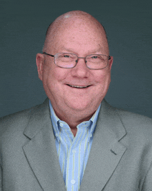 a bald man wearing glasses and a suit is smiling for the camera