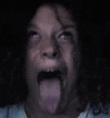 a close up of a person sticking their tongue out in the dark .