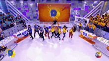 a group of people are dancing on a stage with a sbt logo in the background