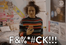 a woman in a striped sweater is holding a cell phone and says f & % * # ck !!!