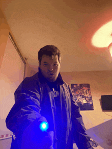 a man in a blue jacket is holding a blue flashlight