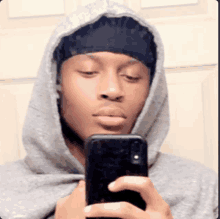 a young man wearing a hoodie is taking a selfie with his cell phone .